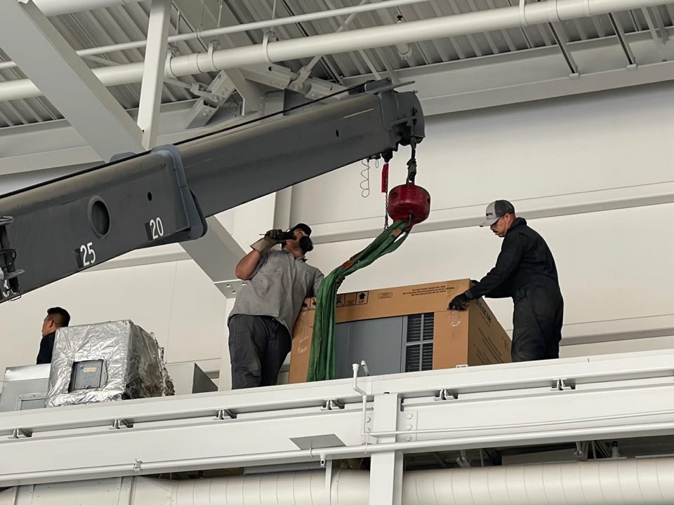Crane lifting refrigeration equipment onto a roof