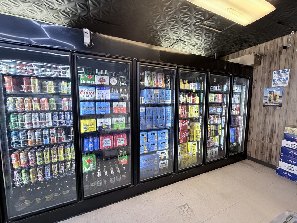 Six glass cooler doors stocked with beer on a liquor store cold wall