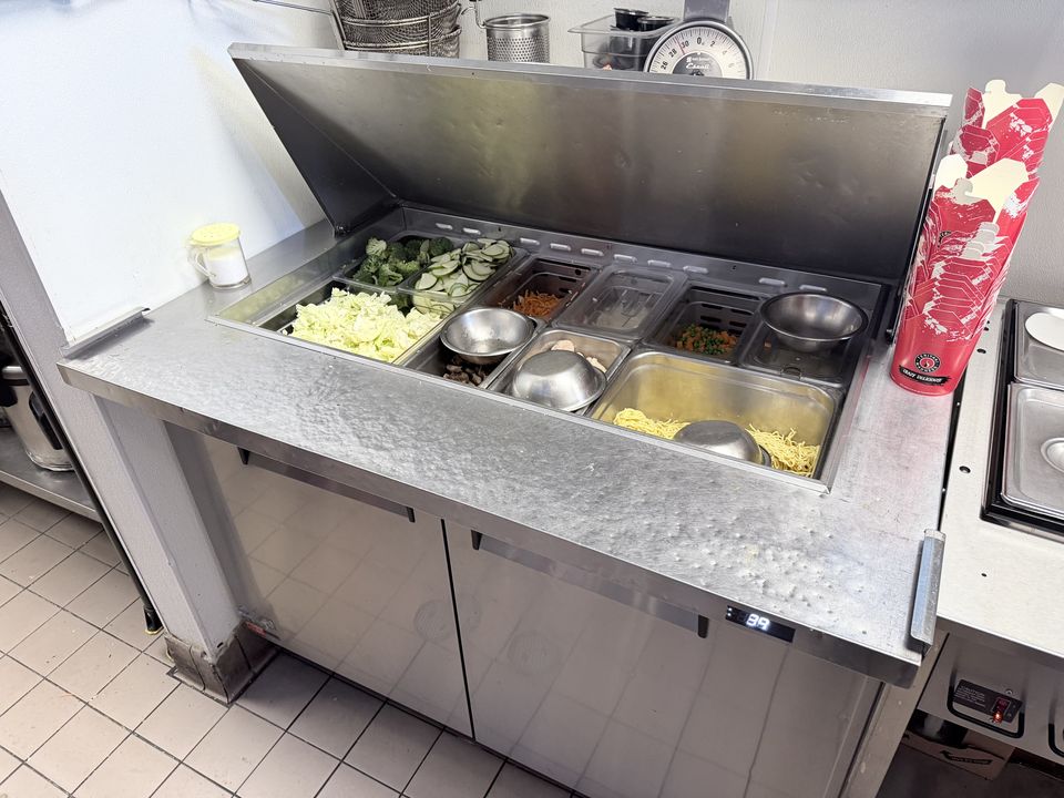 Refrigerated prep table open with chilled ingredients in a restaurant