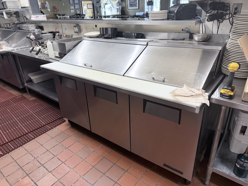 Refrigerated sandwich prep table on a restaurant cook line