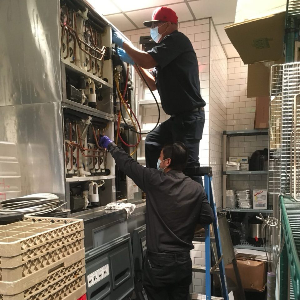 Two Cool Aid technicians working on refrigeration lines in a commercial kitchen