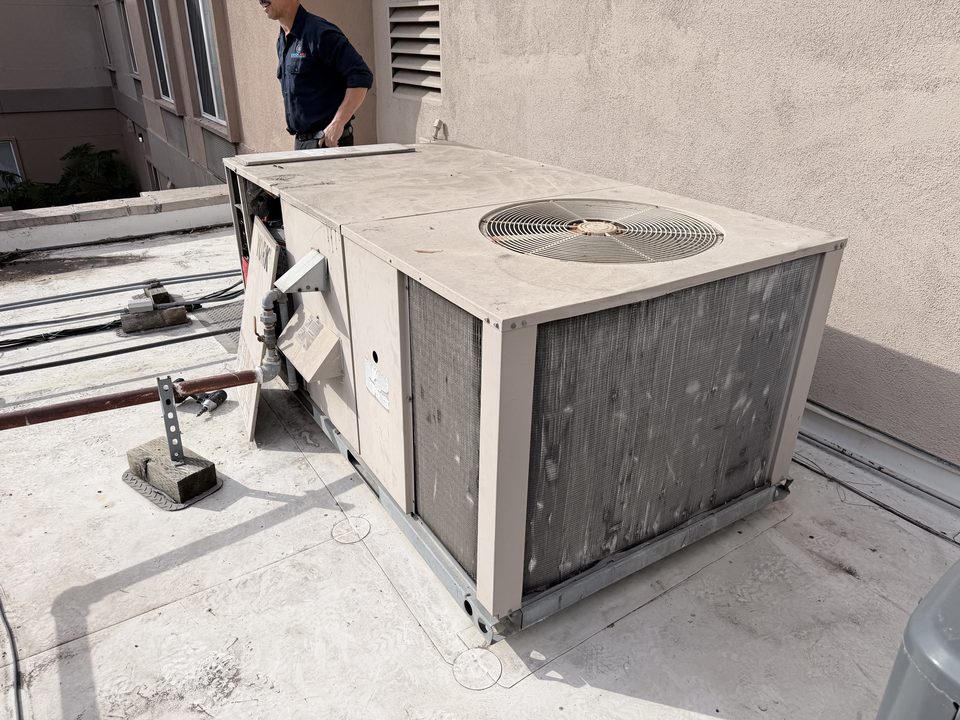 Cool Aid technician beside a York rooftop package unit on a commercial roof